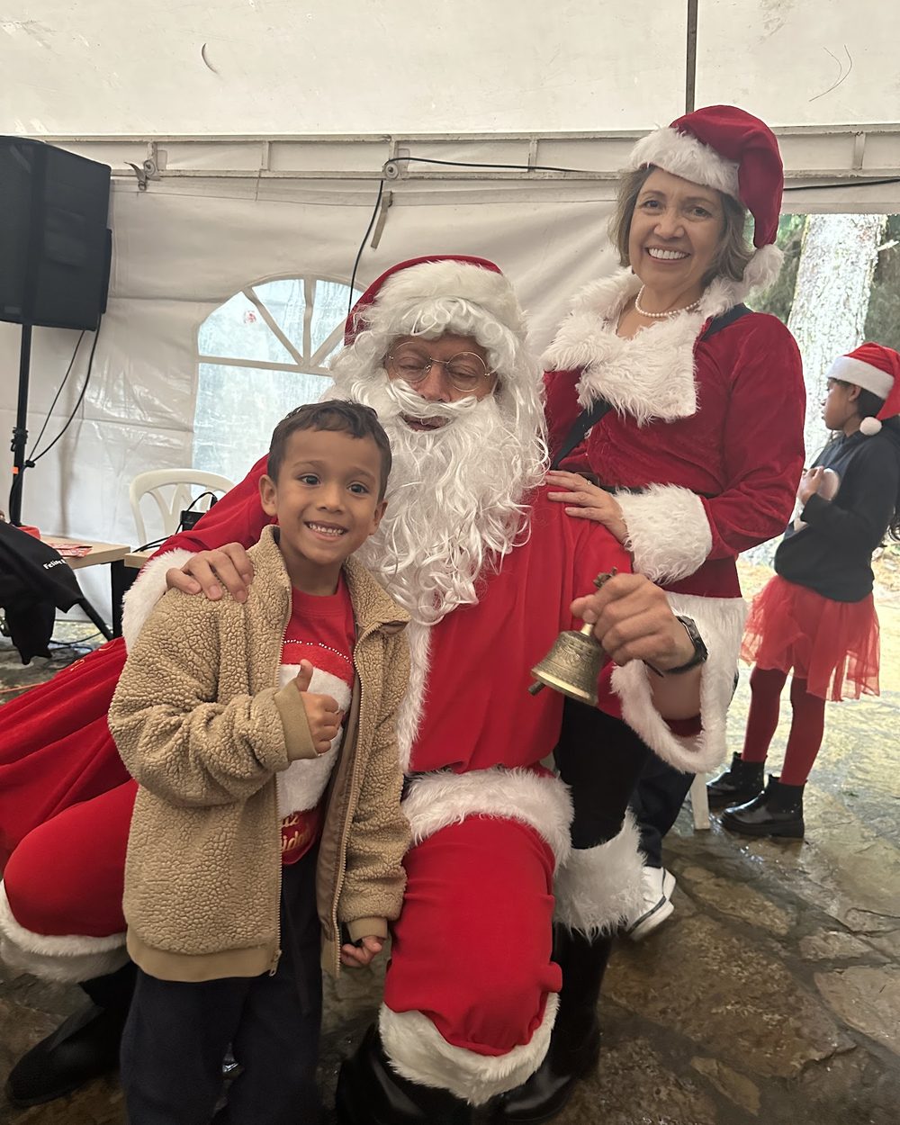 Un niño sonríe junto a Papá Noel y Mamá Noel en el Minimarket Navideño 2025